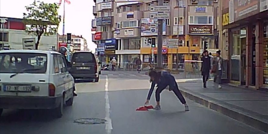 Yola düşen bayrağı araçlar üstünden geçmesin diye aldı
