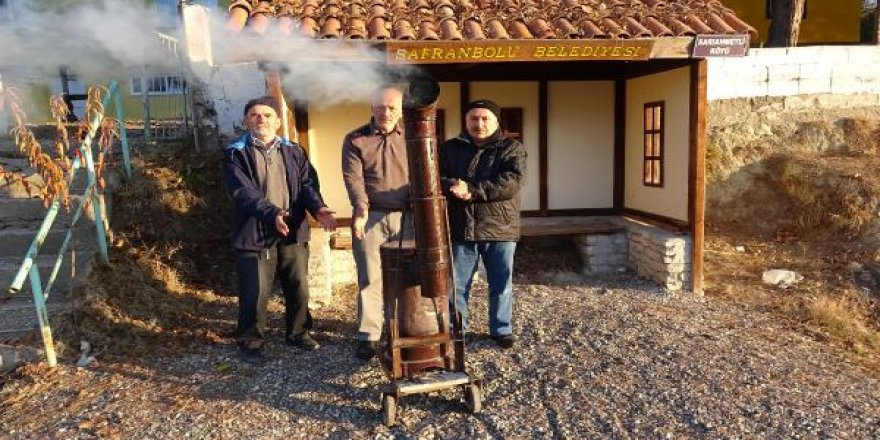 Ekmek almak için bekledikleri durakta seyyar soba ile ısınıyorlar
