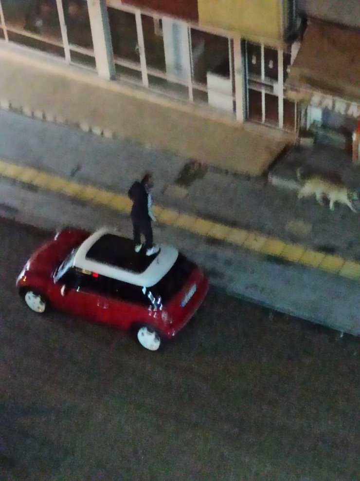 Otomobilin üzerine çıktı, köpekleri çakmakla uzaklaştırmaya çalıştı